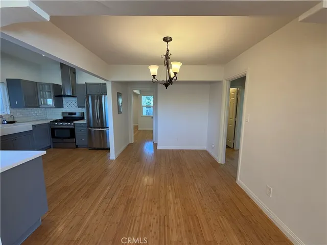 a view of a kitchen with a sink a refrigerator and wooden floor