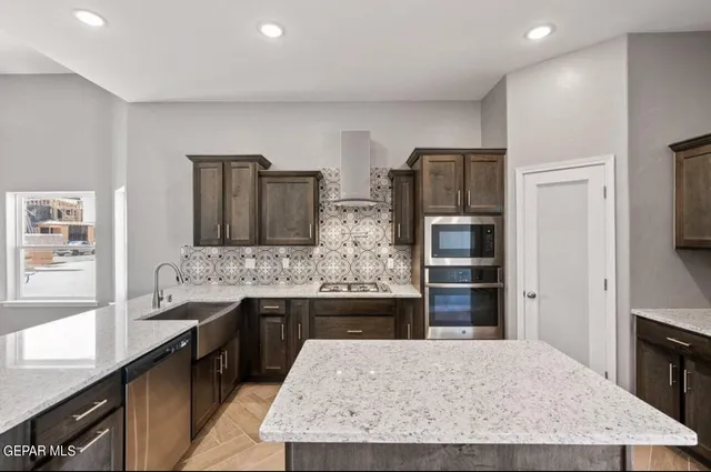 a large kitchen with kitchen island granite countertop a stove refrigerator and cabinets