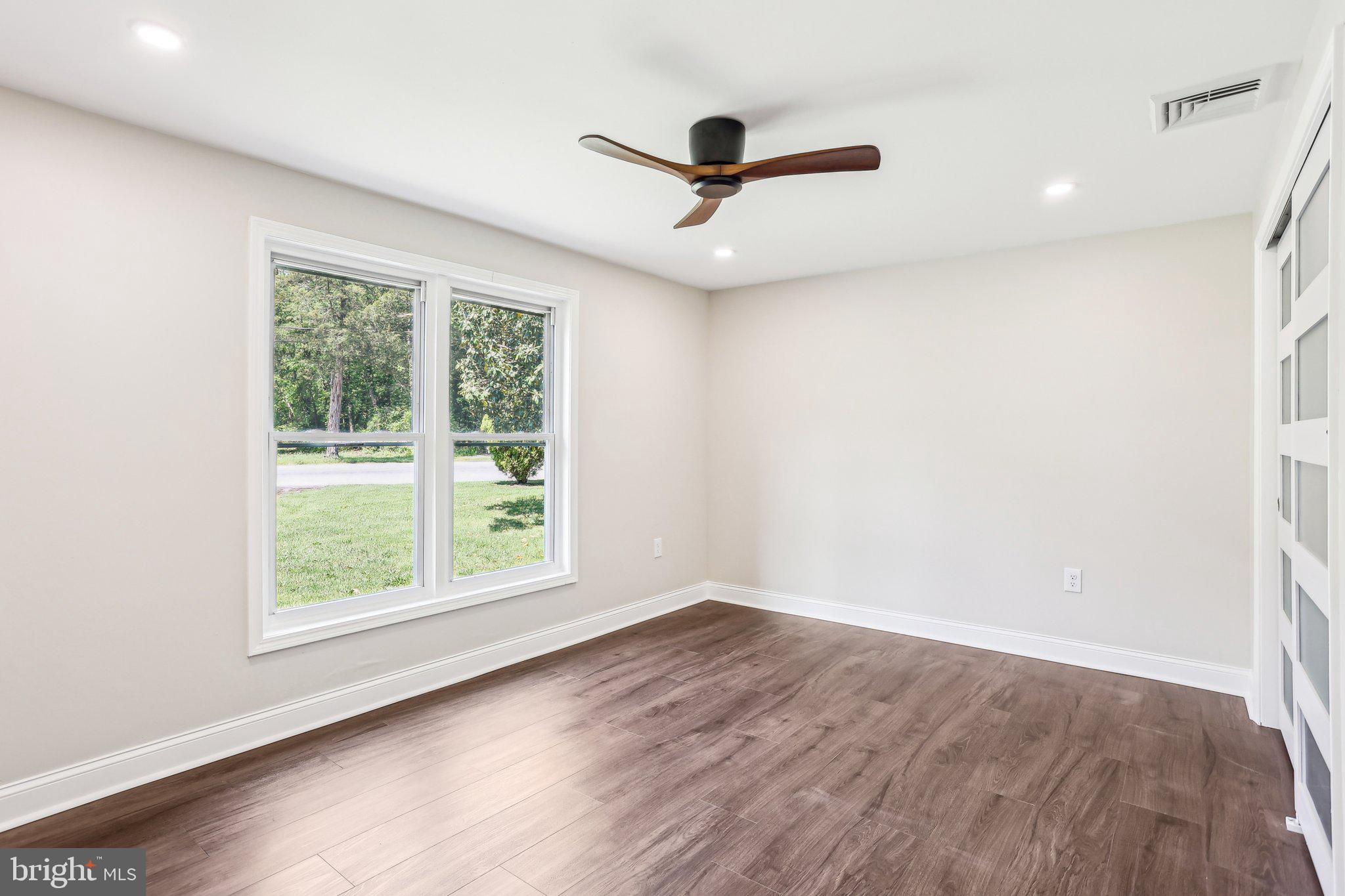 302 Fenwick Road Pilesgrove, NJ 08098 - Photo 27 of 51 an empty room with wooden floor ceiling fan and windows