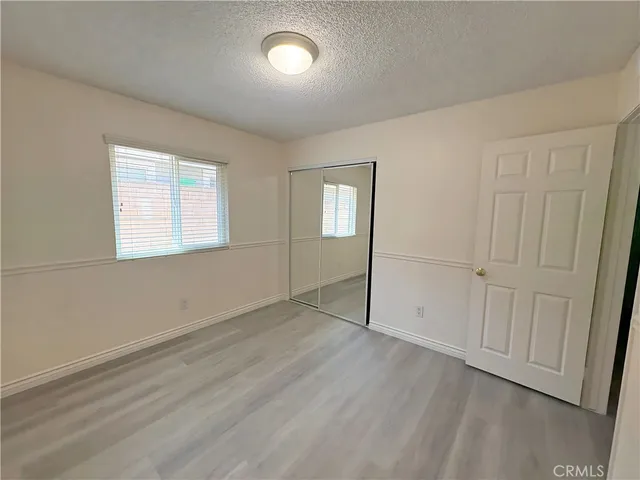 an empty room with wooden floor cabinet and windows