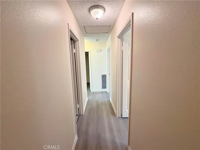 a view of a hallway with wooden floor and a bathroom