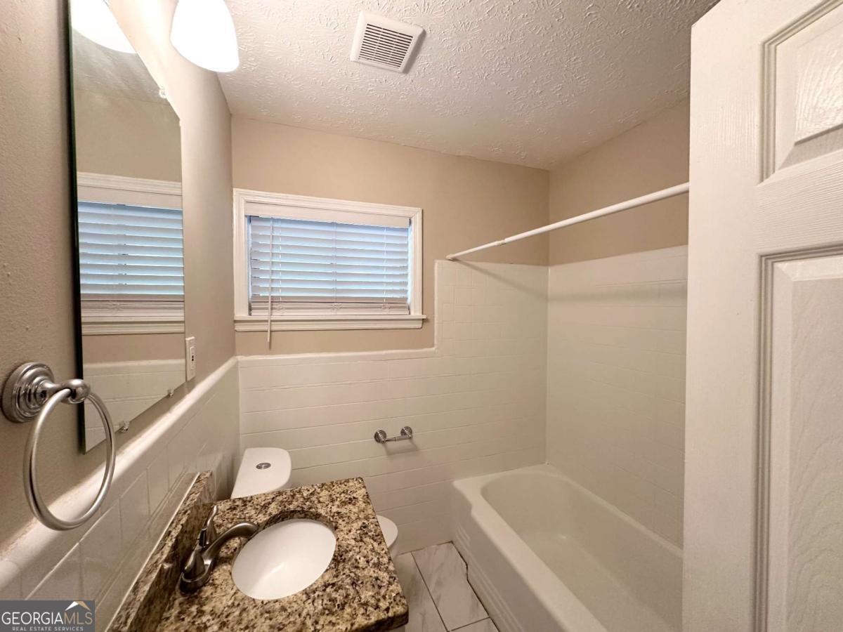 3456 Spring Circle Decatur, GA 30032 - Photo 19 of 22 a bathroom with a granite countertop sink and a bathtub