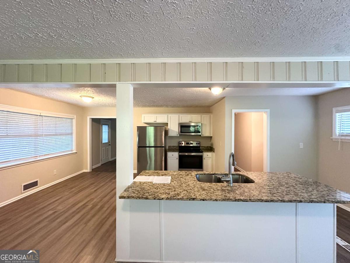 3456 Spring Circle Decatur, GA 30032 - Photo 8 of 22 a kitchen with kitchen island granite countertop wooden cabinets and a counter top space