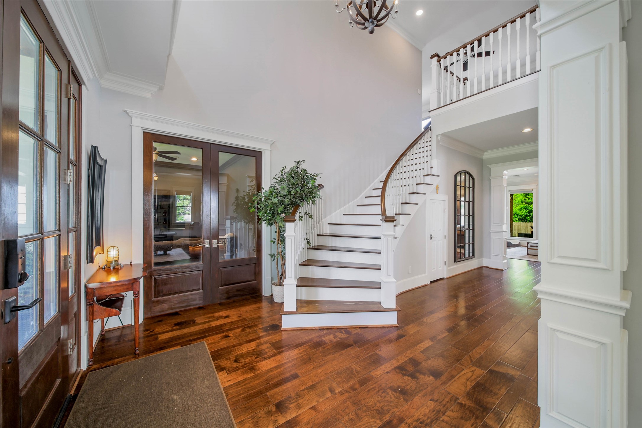 416 West 33rd Street Houston, TX 77018 - Photo 5 of 47 Grand entry featuring a sweeping wood staircase, gorgeous newly refinished wood floors, and exquisite millwork details throughout. Glass-paneled office doors offer the perfect blend of elegance and functionality, while the detailed column craftsmanship adds timeless architectural character to the space.