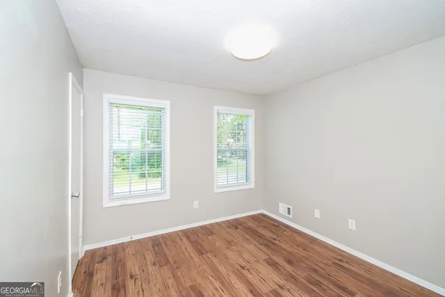 an empty room with wooden floor and windows