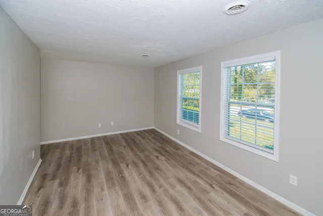 an empty room with wooden floor and windows