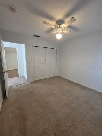 a view of an empty room with a chandelier fan