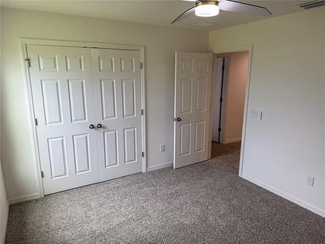a view of an empty room with a chandelier fan