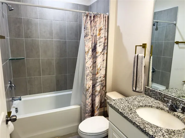 a bathroom with a granite countertop toilet sink and bathtub