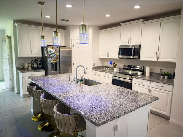 a kitchen with granite countertop kitchen island stainless steel appliances a sink refrigerator and microwave