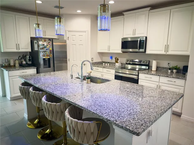 a kitchen with stainless steel appliances granite countertop a sink dishwasher a stove a refrigerator a microwave oven with cabinets and wooden floor