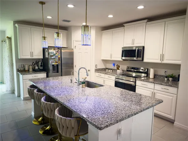 a kitchen with granite countertop kitchen island stainless steel appliances a sink refrigerator and microwave