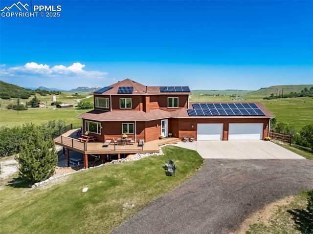 4586 East Best Road Larkspur, CO 80118 - Photo 3 of 50 View of front of property featuring driveway, a wooden deck, and a front yard