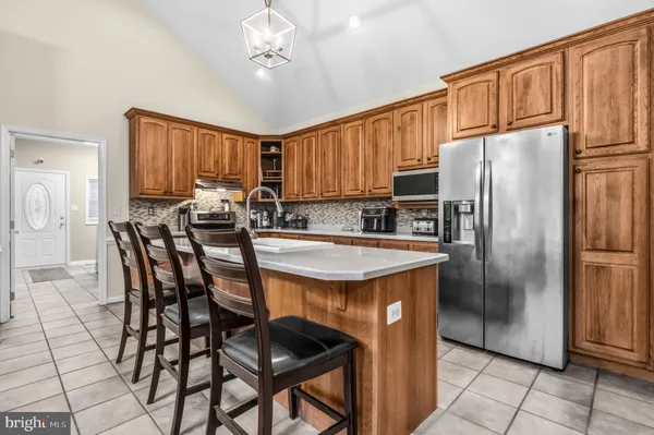 a kitchen with stainless steel appliances granite countertop a refrigerator a stove a sink a dining table and chairs with wooden floor