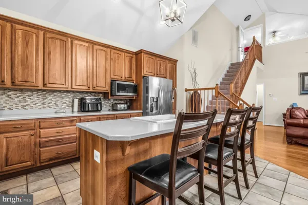 a kitchen with stainless steel appliances granite countertop a stove top oven a sink a dining table and chairs with wooden floor