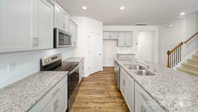 a large kitchen with stainless steel appliances granite countertop a large counter top a stove and a sink