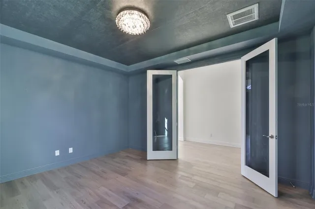 an empty room with wooden floor and a ceiling fan