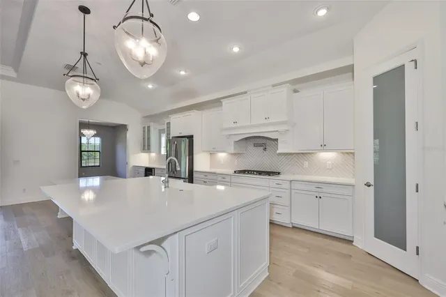 a large kitchen with a large counter top stainless steel appliances and cabinets