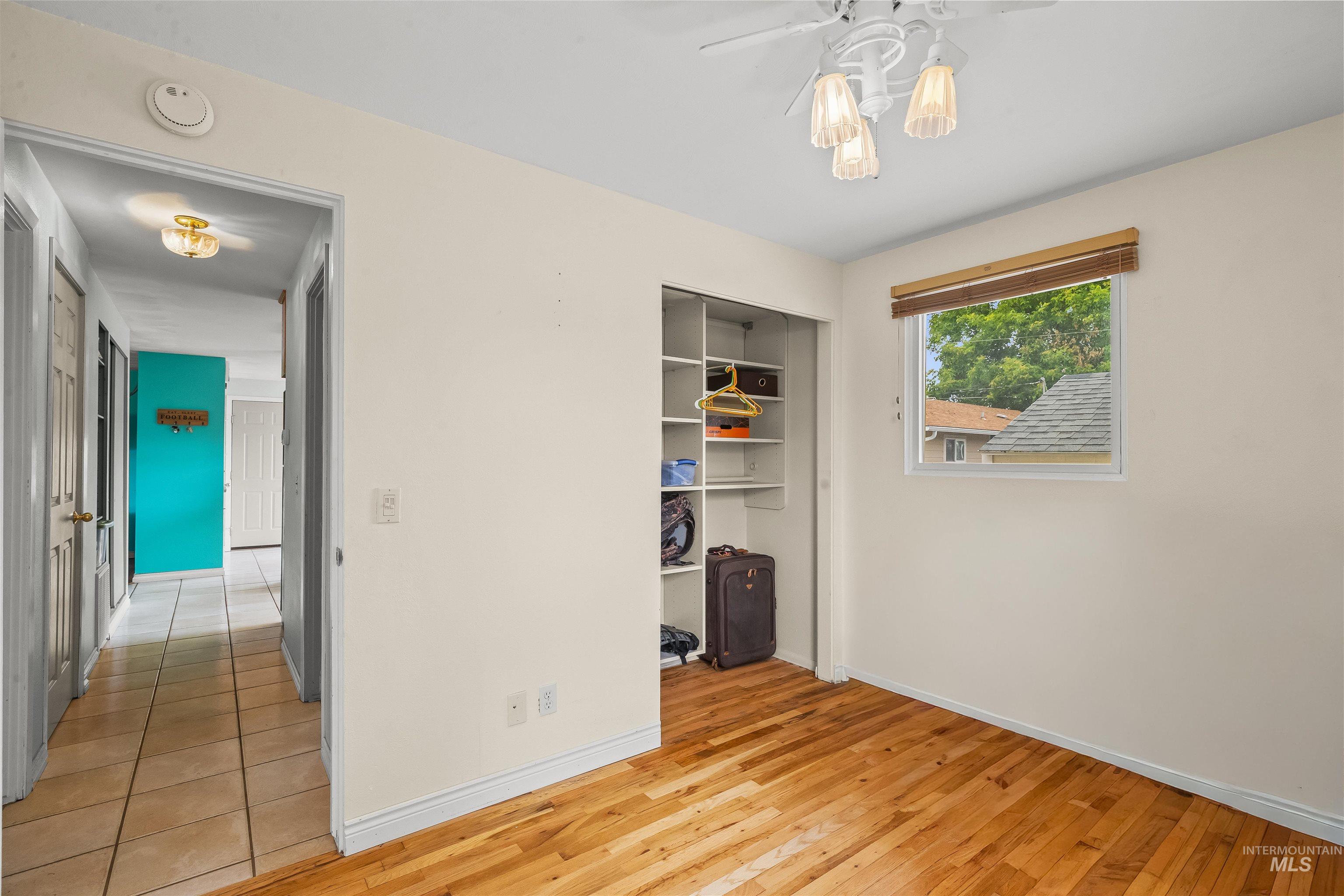 3620 18th Street Lewiston, ID 83501 - Photo 12 of 32 Room featuring wood-finish flooring, a window with a natural wood-tone blind, a ceiling fan with integrated lighting, and a built-in closet with shelving