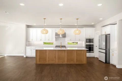 a large kitchen with stainless steel appliances a large counter top a stove and a refrigerator