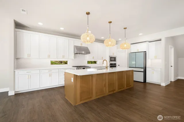 a large kitchen with white cabinets stainless steel appliances a sink and wooden floor
