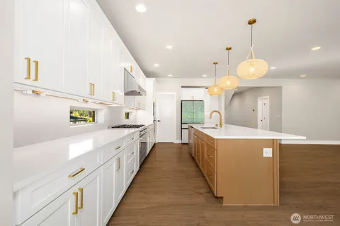 a large kitchen with stainless steel appliances a large counter top a stove and a sink