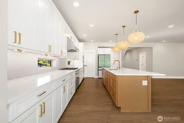 a large kitchen with stainless steel appliances a large counter top a stove and a sink