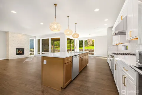 a large kitchen with stainless steel appliances granite countertop a stove and a wooden floors
