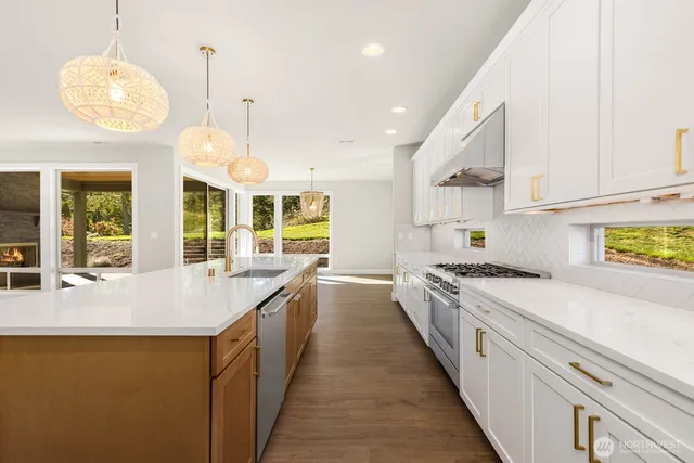 a large kitchen with stainless steel appliances granite countertop a lot of counter space and a wooden floors