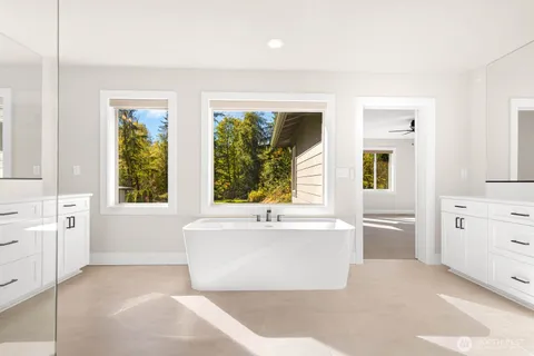 a white bath tub sitting in a en suite bathroom next to a window