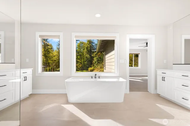 a white bath tub sitting in a en suite bathroom next to a window