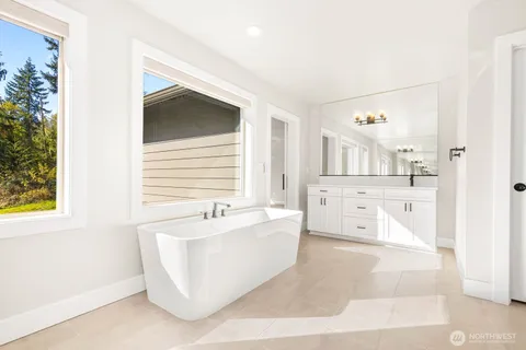 a spacious bathroom with a tub sink and mirror