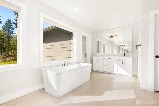 a spacious bathroom with a tub sink and mirror