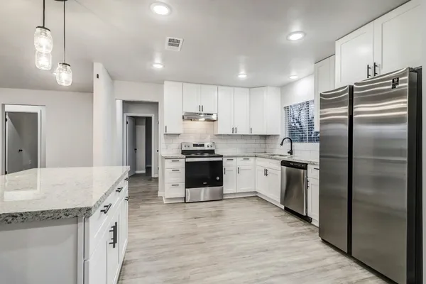 a kitchen with a sink stove cabinets and refrigerator
