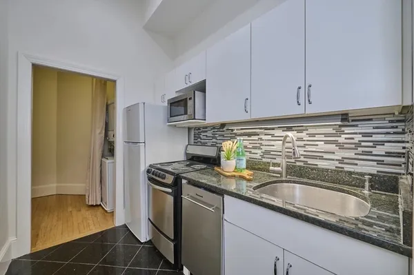 a kitchen with granite countertop a sink stove and refrigerator