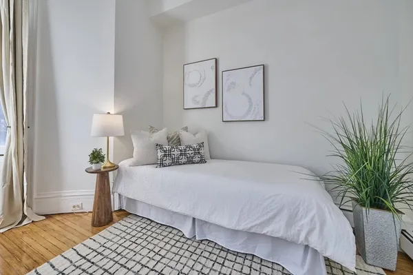 a bedroom with a large bed and a potted plant