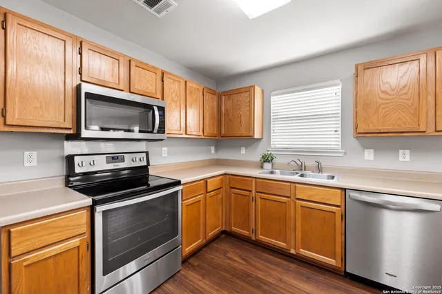 a kitchen with stainless steel appliances granite countertop wooden cabinets a sink a stove a dining table and chairs
