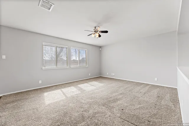 an empty room with windows and ceiling fan