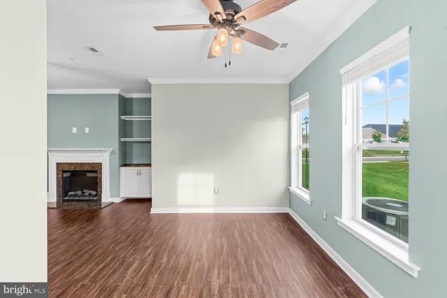 a view of empty room with wooden floor and fan