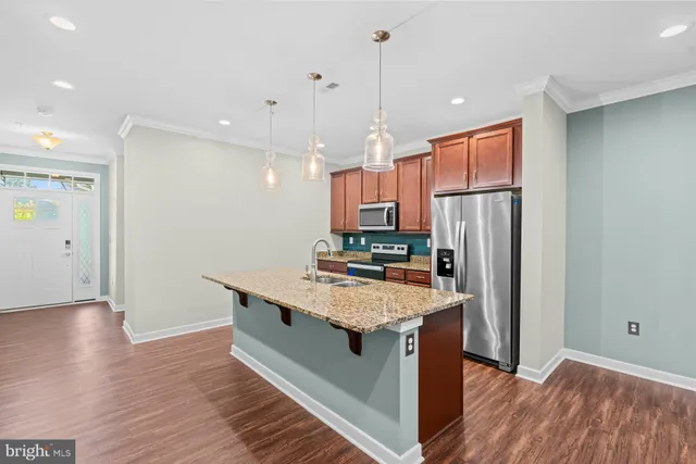 a kitchen with stainless steel appliances granite countertop a kitchen island a hardwood floor and a sink