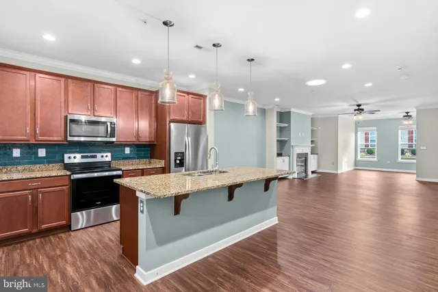 a kitchen with stainless steel appliances granite countertop wooden floors wooden cabinets a stove a sink and a center island