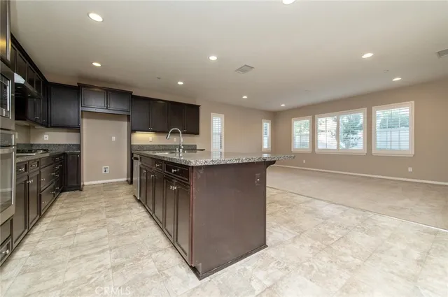 a large kitchen with granite countertop a large counter top stainless steel appliances and cabinets