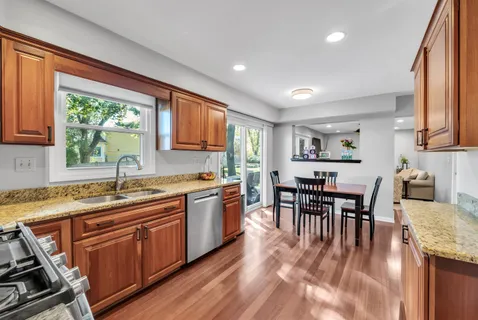 a kitchen with kitchen island granite countertop wooden floors and wooden cabinets
