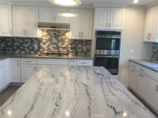 a kitchen with granite countertop white cabinets and stainless steel appliances