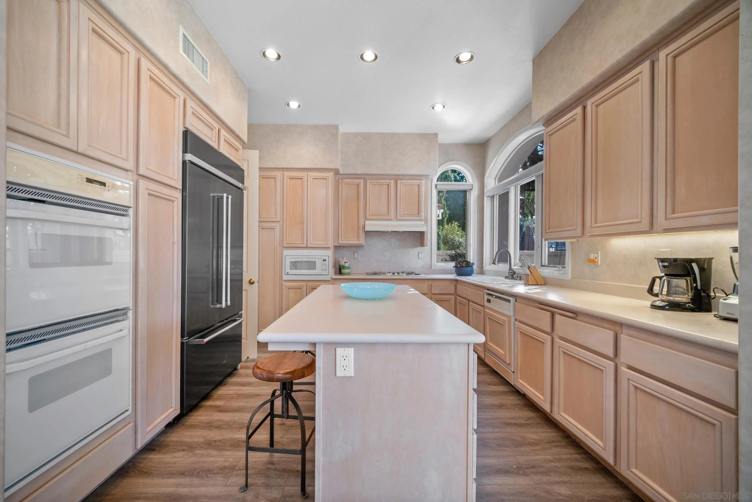 5380 Renaissance Avenue San Diego, CA 92122 - Photo 10 of 25 a kitchen with stainless steel appliances kitchen island granite countertop a refrigerator and a sink