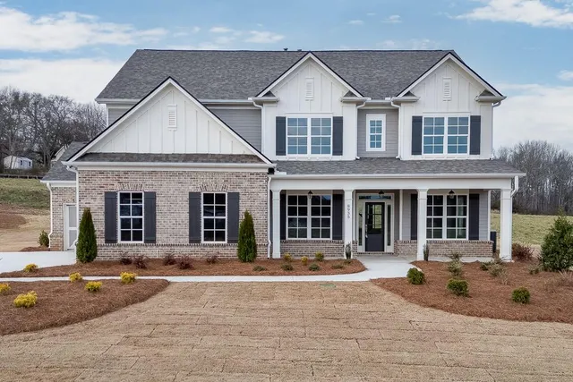 front view of a house with yard and trees in the background
