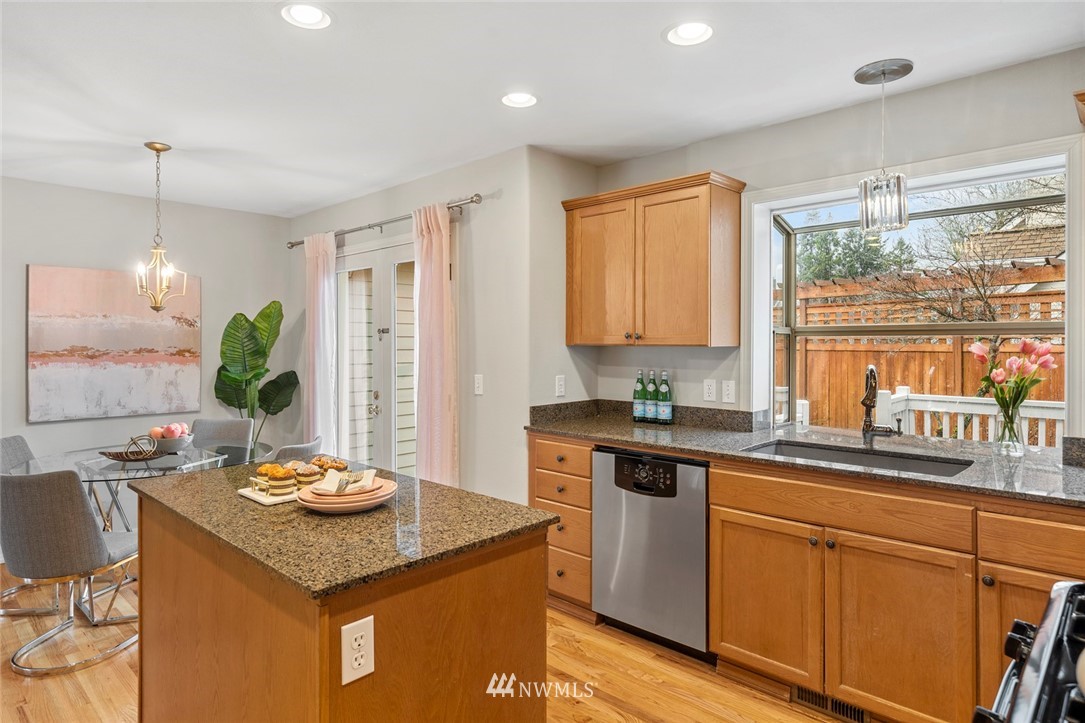 5112 Northeast 20th Street Renton, WA 98059 - Photo 9 of 40 a kitchen with stainless steel appliances granite countertop a sink a stove a dining table and chairs