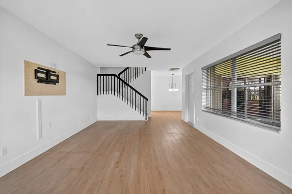 a view of a livingroom with wooden floor a ceiling fan and windows
