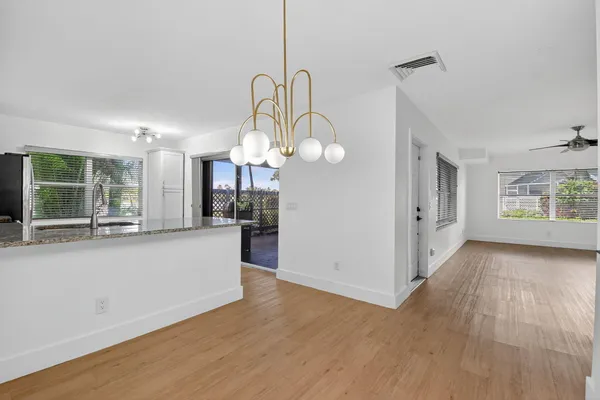 a large kitchen with chandelier and wooden floors