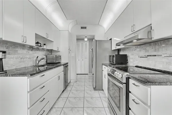 a kitchen with granite countertop a sink stove and refrigerator